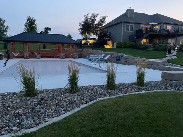 pool with river rock landscape and gazebo by house