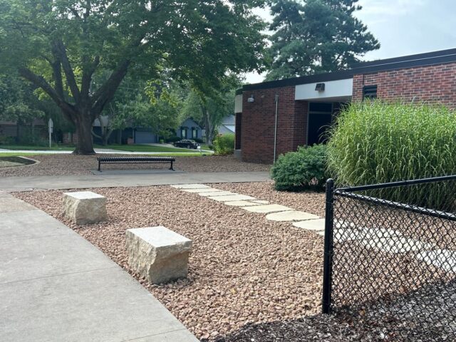 school with stone path and large stone benches in rocky area and tall grass